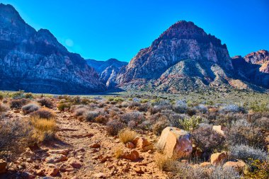 Las Vegas Nevada yakınlarındaki Kızıl Kaya oluşumlarının nefes kesici görüntüsü. Berrak mavi gökyüzünün altındaki engebeli dağlar çöl güzelliğinin ve maceranın özünü keşfetmeye ve yakalamaya davet ediyor..