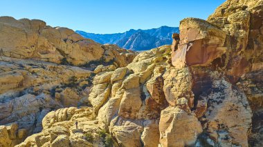 Las Vegas yakınlarındaki Calico Tank Patikası boyunca Kızıl Kaya Kanyonu 'nun canlı kumtaşı oluşumlarının nefes kesici görüntüsü. Bu ikonik Nevada manzarasının engebeli güzelliğini ve ihtişamını tecrübe edin..