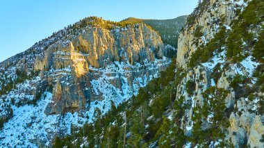 Nevada 'daki Charleston Dağı' nın görkemli hava manzarası, karla kaplı uçurumlar ve gür kozalaklı ormanlar. Altın ışık, bu el değmemiş dağ manzarasının engebeli güzelliğini vurgular..