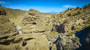 Las Vegas yakınlarındaki Nevada engebeli çöl manzarası. Görkemli kaya oluşumları ve Charleston Dağı silueti açık mavi gökyüzü karşısında Amerikan Güneybatısının güzelliğini gözler önüne seriyor..
