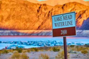 Boulder City Nevada yakınlarındaki Mead Gölü 'nde altın saat. Tabela, 2000 su hattını işaret ediyor. Bugünkü düşük seviyeler tamamen zıt. Kuraklığın bu çöl manzarasına etkisini hatırlatan dokunaklı bir hatırlatma..