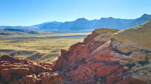 Nevada 'daki Kızıl Kaya Kanyonu' nun canlı kumtaşı oluşumlarının havadan görünüşü, Las Vegas 'ta Calico Tank Patikası' nın yakınlarında muazzam mavi gökyüzü altında çarpıcı bir manzara sanatsal özellikleri sergiliyor..