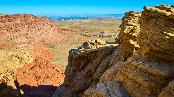 Calico Tank Yolu yakınlarındaki Kızıl Kaya oluşumlarının hava görüntüsü Nevada 'daki açık mavi gökyüzünün altında Las Vegas ufuk çizgisine karşı dramatik çöl manzarasını sergiliyor..