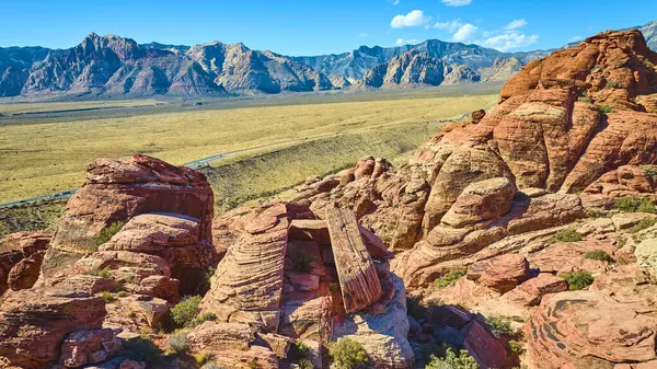 Göz kamaştırıcı Kızıl Kaya Kanyonu, Nevada 'nın hava manzarası açık mavi gökyüzü altında canlı kumtaşı katmanları ve geniş çöl yolları sergiliyor. Macera ve doğal güzellik temaları için mükemmel..