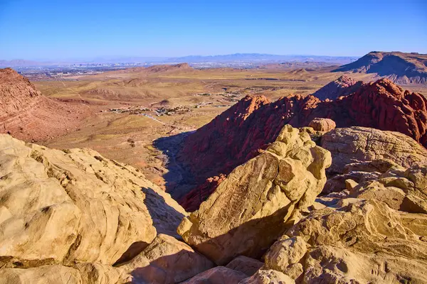 Las Vegas yakınlarındaki Red Rock Kanyonu 'nun nefes kesici manzarası. Serüven ve yalnızlığı keşfedin. Canlı çöl, açık mavi gökyüzünün altındaki uzak şehir manzarasıyla buluşur..