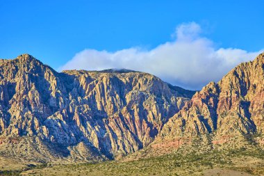 Nevada 'daki Kızıl Kaya Kanyonu' nun engebeli güzelliğini keşfedin. Las Vegas yakınlarındaki bu canlı çöl manzarası parlak mavi gökyüzünün altındaki kayalık dağların ve dingin patikaların nefes kesici manzarasını sunuyor..