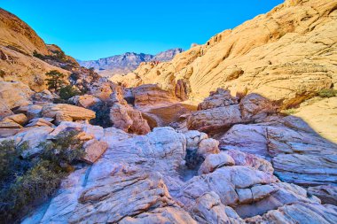 Nevada, Red Rock Canyon 'daki Calico Tanks Trail' de altın saat. Engebeli turuncu kaya oluşumları ve canlı mavi bir gökyüzü macera arayanlar için mükemmel dramatik ve nefes kesici bir çöl manzarası yaratır..