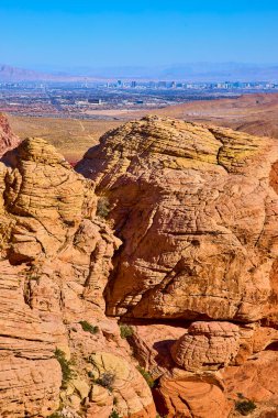 Calico Tanks Patikası 'ndan çarpıcı manzara Kızıl Kayalar' ı sergiliyor. Uzakta Las Vegas silueti var. Parlak mavi gökyüzünün altında doğal güzelliğin ve şehir hayatının mükemmel bir karışımı..