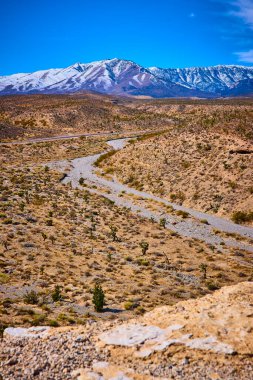 Berrak mavi gökyüzünün altındaki Nevadas Dağı 'nın saf güzelliğini keşfedin. Karla kaplı tepeler ve dolambaçlı bir çöl nehri bu sakin güneybatı manzarasında çarpıcı bir kontrastlık yaratır..