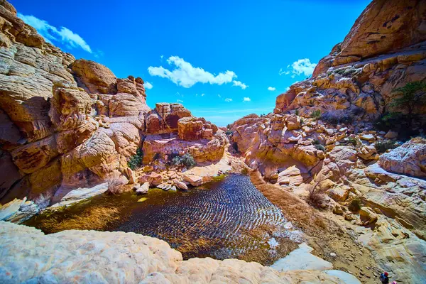 Las Vegas, Nevada 'daki çarpıcı Calico Tanklarını keşfedin. Parlak mavi bir gökyüzünün altında sakin bir göleti çevreleyen engebeli kırmızı kaya oluşumlarına hayret. Seyahat ve macera meraklıları için mükemmel..