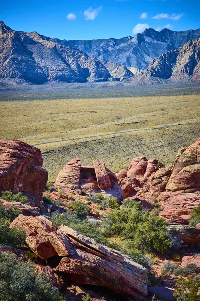 Nevada 'daki çarpıcı Kızıl Kaya Kanyonu' nu keşfedin. Parlak kumtaşı oluşumları ve yemyeşil alanlar, berrak mavi gökyüzünün altındaki geniş çöl ve görkemli dağlarla güzel tezat oluşturur..