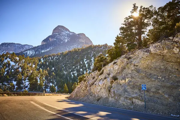 Nevada 'daki Charleston Dağı' nda altın saat parlıyor. Dolambaçlı bir yol, keşfi hiç bitmeyen yeşil ağaçların ve karla kaplı tepelerin arasına davet eder. Seyahat reklamları için mükemmel doğa, dingin güzellik ve macera..