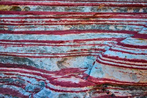 Calico, Las Vegas 'taki katmanlı tortul kayanın yakın çekimi. Çarpıcı kırmızı ve beyaz bantlar sanatsal yapıyı ve zamanın akışını sergiliyor, Amerikan halkının karmaşık dokusunu vurguluyor.