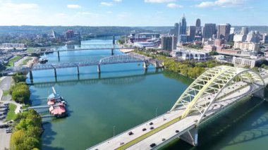 Gökyüzü Uçuşu: Cincinnatis 'i yukarıdan canlı bir şekilde tecrübe edin, Ohio Nehri üzerinde ikonik köprüler ve mavi gökyüzünün altında çarpıcı bir gökyüzü, kentsel cazibeyi doğal güzellikle harmanlayan.