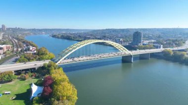 Aerial Arc Shot: Cincinnatis 'in Ohio Nehri üzerindeki ikonik köprüye odaklanarak nefes kesici ufuk çizgisini deneyimlemek, kentsel mimariyi bu büyüleyici dron görünümündeki doğal güzellikle harmanlamak.