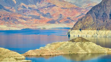 Mead Gölü 'nün havadan görünüşü: Boulder City, Nevada yakınlarındaki engebeli tepeler tarafından çerçevelenmiş, altın saat ışığını yansıtan derin mavi sular. Açık hava eğlencesi ve doğal güzellik temaları için mükemmel..