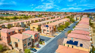 Las Vegas, Nevada 'da planlanmış bir banliyö topluluğunun hava görüntüsü. Terracotta çatıları ve güneş panelleri çöl manzarasıyla harmanlanmış, çevre dostu yaşam ve modern şehir planlaması sergilenmektedir..