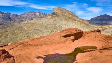 Nevadas 'taki Turtlehead Tepesi' nin nefes kesici çöl manzarasına karşı Kızıl Kaya Kanyonlarının çarpıcı kumtaşı oluşumları ve sakin su havuzunun havadan görünüşü..