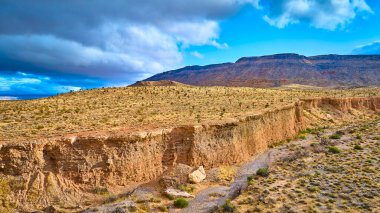 Las Vegas yakınlarındaki Kızıl Kaya Kanyonu 'nun havadan görünüşü çarpıcı bir çöl manzarası yakalar. Dramatik gölgeler ve altın renkler dramatik bir gökyüzü altında engebeli araziyi aydınlatıyor, macera ve yalnızlığı çağrıştırıyor..