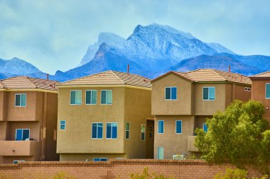 Las Vegas, Nevada banliyölerindeki modern sıva evleri, kar tozuyla kaplı Charleston Dağı 'nın çarpıcı zeminine karşı durmaktadır. Amerika 'da çağdaş yaşam ve doğal güzelliğin karışımını deneyimleyin.