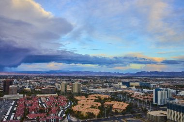Las Vegas 'ın havadan görünüşü, ikonik yüksek dönme dolap, dramatik bulutlar ve kentsel dayanıklılık ve güzelliği gözler önüne seren uzak dağlar ile canlı şehir manzarası ile doğayı yakalar..