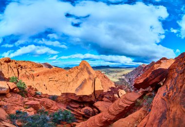 Las Vegas, Nevada yakınlarındaki Red Rock Kanyonu nefes kesici bir manzara. Parlak mavi gökyüzü altında canlı kırmızı ve turuncu kaya oluşumları açık hava macerası ve doğal güzelliğin özünü yakalar..