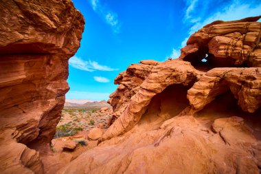 Nevada 'daki Ateş Vadisi' nin nefes kesici güzelliğini tecrübe edin. Canlı kırmızı kaya oluşumları geniş bir çöl zeminine karşı duruyor. Seyahat promosyonları ve açık hava macera temaları için mükemmel..