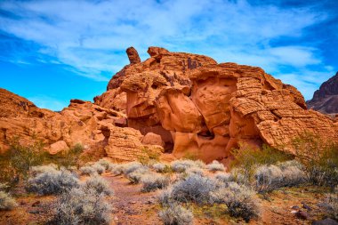 Nevada, Boulder City 'de Redstone Dune' un çarpıcı kızıl kaya oluşumlarını keşfedin. Açık mavi gökyüzünün altındaki bu çöl manzarasının canlı renklerini ve engebeli güzelliğini hissedin..