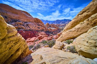Nevada 'daki Red Rock Kanyonu' nun canlı katmanlarını keşfedin. Açık mavi gökyüzü altında yükselen kırmızı ve kumlu oluşumlar bu büyüleyici çöl manzarasında macera ve huşu uyandırıyor..