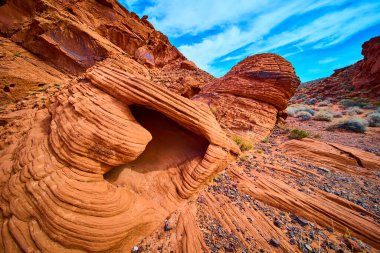 Nevada, Boulder City Redstone Dune 'daki canlı kumtaşı oluşumlarının nefes kesici görüntüsü. Canlı turuncu ve kırmızı katmanlar berrak mavi gökyüzünün altında çarpıcı bir çöl manzarası yaratıyor..