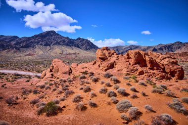 Nevadas Ateş Vadisi 'ndeki göz kamaştırıcı kırmızı kumtaşı oluşumları açık mavi gökyüzü ile tezat oluşturuyor. Engebeli arazi ve seyrek bitki örtüsü macera ve keşif için mükemmel bir manzara yaratır..