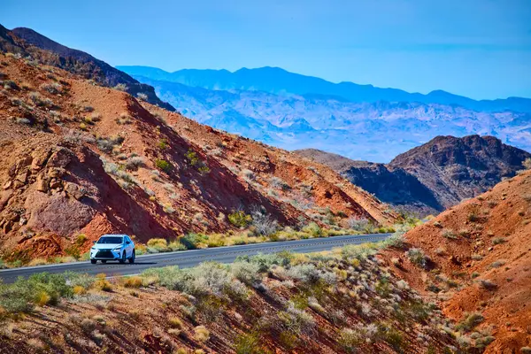 Nevadas Northshore Yolu 'nun engebeli kırmızı kaya oluşumlarında beyaz bir SUV' un gezindiği destansı bir maceraya atlayın. Uçsuz bucaksız çöl manzaraları ve açık mavi gökyüzü arasında keşfin heyecanını hissedin..