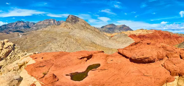 Kızıl Kaya Kanyonu, Nevada 'nın havadan görünüşü: Pas rengi kumtaşı oluşumları ve nadir bir su havuzu açık mavi gökyüzü altında dramatik bir manzara yaratır. Doğa, jeoloji ve seyahat için mükemmel..