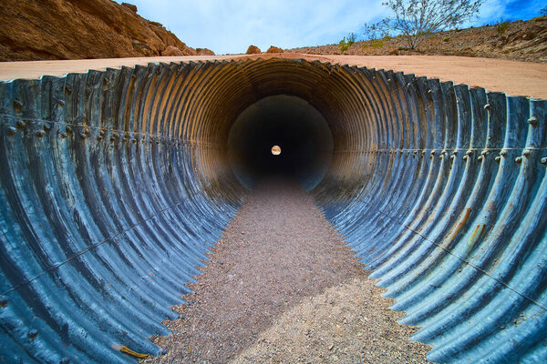 Explore the depths of infrastructure with this striking image of a corrugated metal drainage pipe in Boulder City Nevada, showcasing engineering amidst a stark desert landscape.