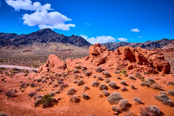 Nevadas Ateş Vadisi 'ndeki göz kamaştırıcı kırmızı kumtaşı oluşumları açık mavi gökyüzü ile tezat oluşturuyor. Engebeli arazi ve seyrek bitki örtüsü macera ve keşif için mükemmel bir manzara yaratır..