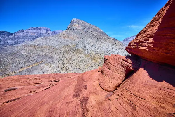Las Vegas, Nevada yakınlarındaki çarpıcı Kızıl Kaya Kanyonunu keşfedin, parlak kırmızı kumtaşı oluşumlarına ve berrak mavi gökyüzünün altındaki görkemli dağlara hayret edin, bir maceracılar çöl cenneti.
