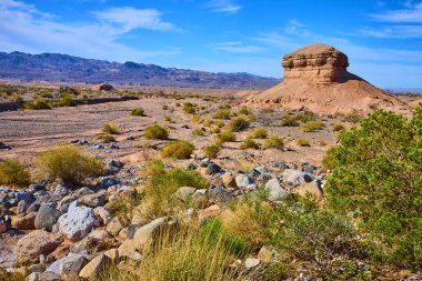 Nevadas Northshore Yolu 'nun engebeli güzelliğini keşfedin. Uçsuz bucaksız, berrak mavi gökyüzünün altındaki uzak dağ sıraları tarafından çerçevelenmiş kurak çöl manzarasından çarpıcı bir butte yükselir..