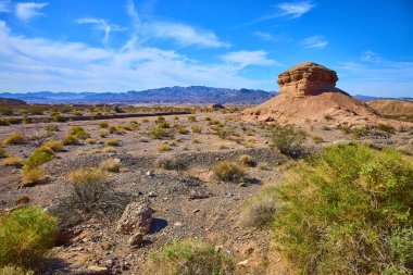 Büyük çöldeki Nevadas Northshore Yolu üzerinde görkemli kaya oluşumları kulesi. Parlak mavi gökyüzünün altındaki kurak araziyi kaplayan seyrek çalılar bu zamansız manzaranın engebeli güzelliğini yakalıyor..