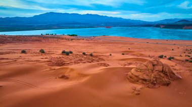 Canlı kırmızı kum tepelerinin havadan görünüşü, sakin mavi bir rezervuar, ve Sand Hollow State Park Utah 'taki uzak dağlar macera gezisi için mükemmel açık hava eğlencesi ve manzaralı yol teması.