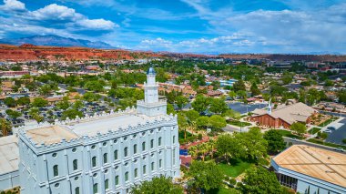 St. George Utah 'ın havadan görünüşü çarpıcı beyaz St. George Utah Tapınağı, klasik bir kırmızı tuğlalı kilise ve Amerikan güneybatısındaki parlak bir gökyüzü altında dramatik kırmızı kaya oluşumları.