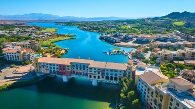 Renkli kemerli bir köprünün ve Las Vegas Gölü 'ndeki Akdeniz tarzı bir köyün havadan görünüşü. Kıyıdaki palmiye ağaçları ve çöl tepeleri parlak mavi gökyüzü lüks bir tatil köyünün altında yaşıyor.