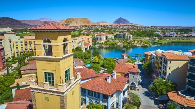 Güneşli bir günde Las Vegas Gölü 'nde çöl dağlarına karşı uzun sarı çan kulesi, sakin göl ve bereketli peyzaj manzaralı canlı bir Akdeniz tarzı köy.