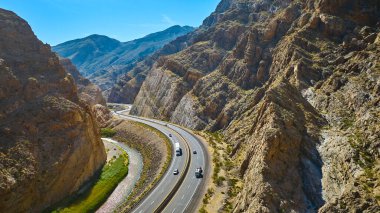 Virgin River Gorge Arizona 'daki dik kanyon duvarlarını kesen dolambaçlı bir otoyol ve nehir manzarası. Kamyonlar ve arabalar uçsuz bucaksız mavi gökyüzünün altında bu manzaralı çöl yolunda seyahat ederler..