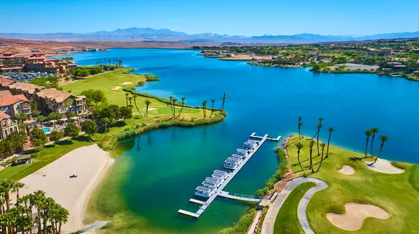Las Vegas Gölü 'ndeki lüks göl kenarı topluluğunun havadan görünüşü. Işıldayan mavi su, yemyeşil golf sahası ve lüks evler çöl güneşinde konaklama ve lüks gayrimenkulleri gösteriyor.