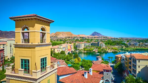 Akdeniz 'den esinlenilmiş bir kule ve Las Vegas Gölü' ndeki sakin mavi gölün yanındaki renkli binalar. Arka planda çöl dağları ve yukarıdaki parlak yaz gökyüzü.