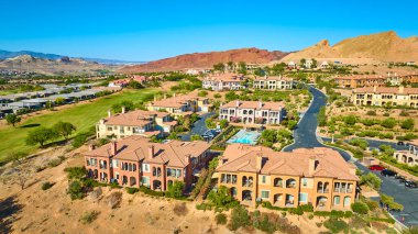 Las Vegas Gölü 'ndeki lüks Akdeniz villaları. Manikürlü bahçeleri, merkezi havuzu ve açık mavi gökyüzünün altındaki çöl dağlarıyla çevrili yemyeşil bir golf sahası.