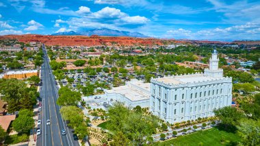 St. George Utah 'ın ikonik beyaz St. George Utah Tapınağı' nı gösteren hava manzarası. Parlak bir gün ortası gökyüzünün altında parlak kırmızı kaya kayalıkları ve tasarrufları olan yeşil bahçeler arasında yuva yapmış.