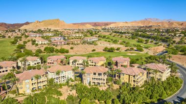 Las Vegas Gölü 'ndeki lüks Akdeniz tarzı villaların ve yemyeşil golf sahasının havadan görünüşü, canlı mavi gökyüzü altında çöl tepelerinin arasına kurulmuş, lüks emlak ve yaşam tarzı temaları için mükemmel.