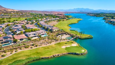 Las Vegas Gölü 'ndeki lüks göl golf topluluğunun hava manzarasında modern evler, manikürlü yollar, parlak mavi sular ve güneşli gökyüzünün altında manzaralı çöl dağları.