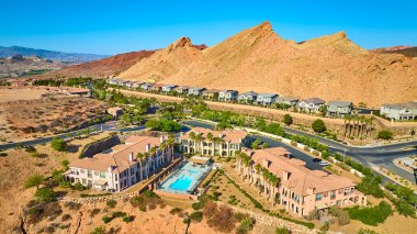 Modern evlerin yakınındaki havuz ve palmiye ağaçları ve Las Vegas Gölü 'ndeki dramatik dağlarla dolu, güneşli gökyüzü altında lüks bir Akdeniz tarzı konut kompleksi.